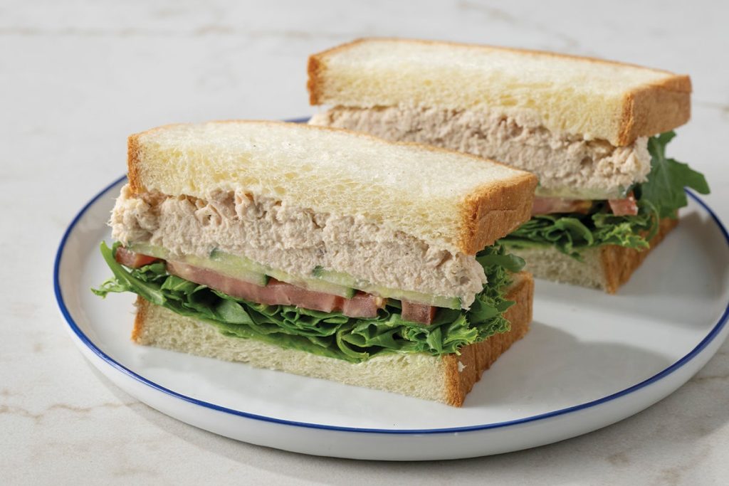 Tuna Sandwich with Cucumber and Tomato Cut in Half on White Plate